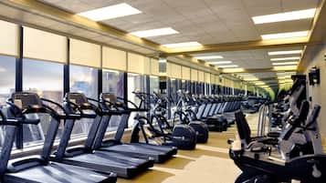 Une salle de sport équipée de nombreux tapis de course et d’appareils d’exercice disposés en rangées.