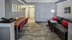 A modern hotel room with a wooden desk, a sofa, and a patterned carpet. - Hampton Inn Batesville (Batesville)