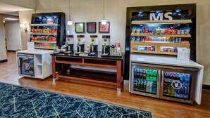 A hotel lobby with a snack bar, coffee machines, and refrigerated beverage dispensers. - Hampton Inn Batesville (Batesville)