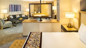 A hotel room with a bed, a sofa, a small table, a mirror, and a lamp.
