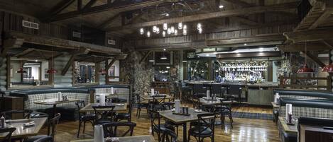 A rustic interior with wooden beams, a bar area, and seating arrangements.