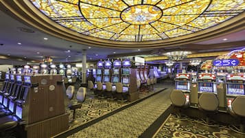 A casino with multiple slot machines, a patterned carpet, and a large stained glass ceiling.