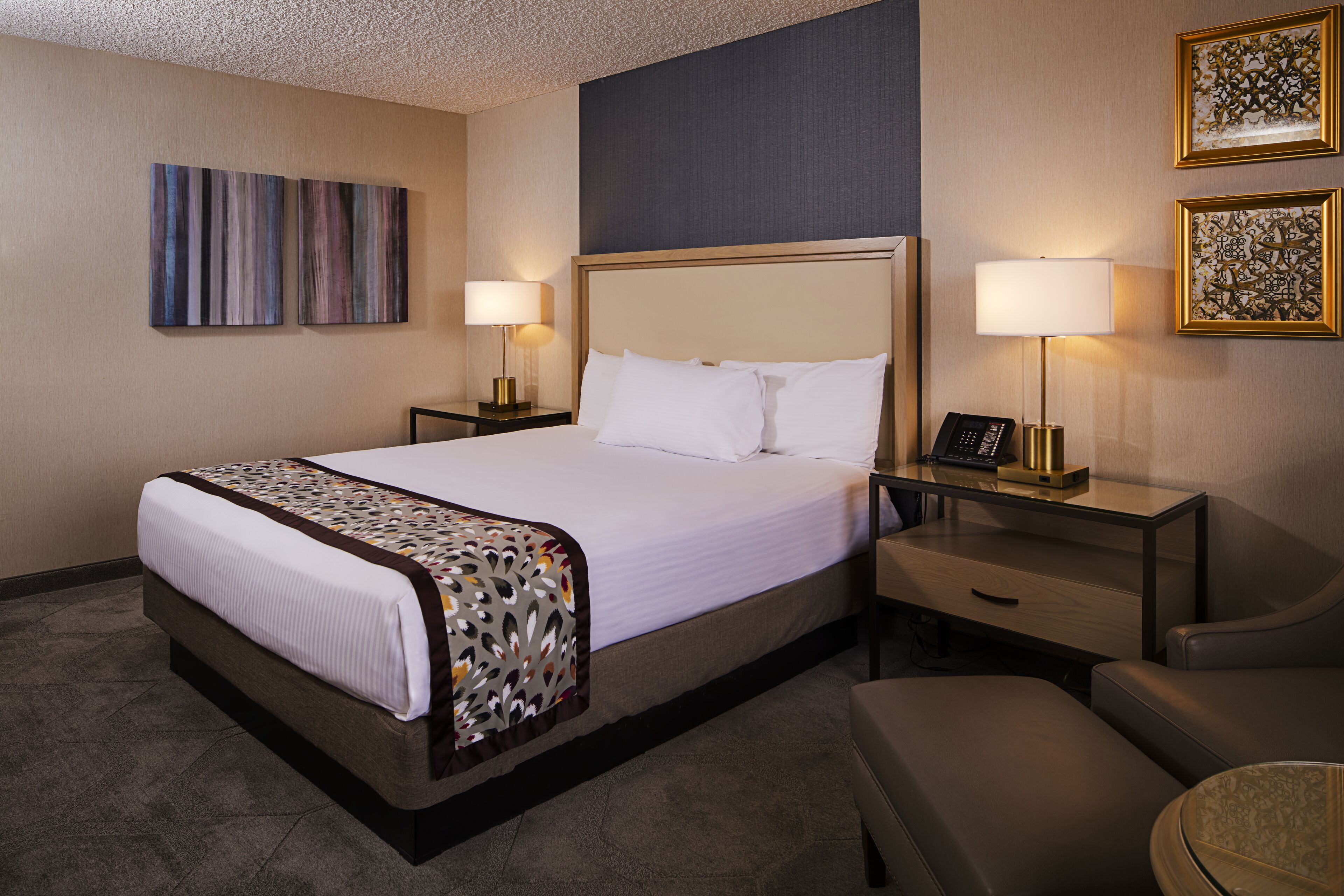 A hotel room with a large bed, two bedside tables with lamps, a desk, and a chair.