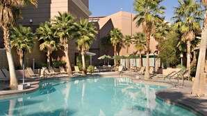 A swimming pool surrounded by palm trees and lounge chairs.