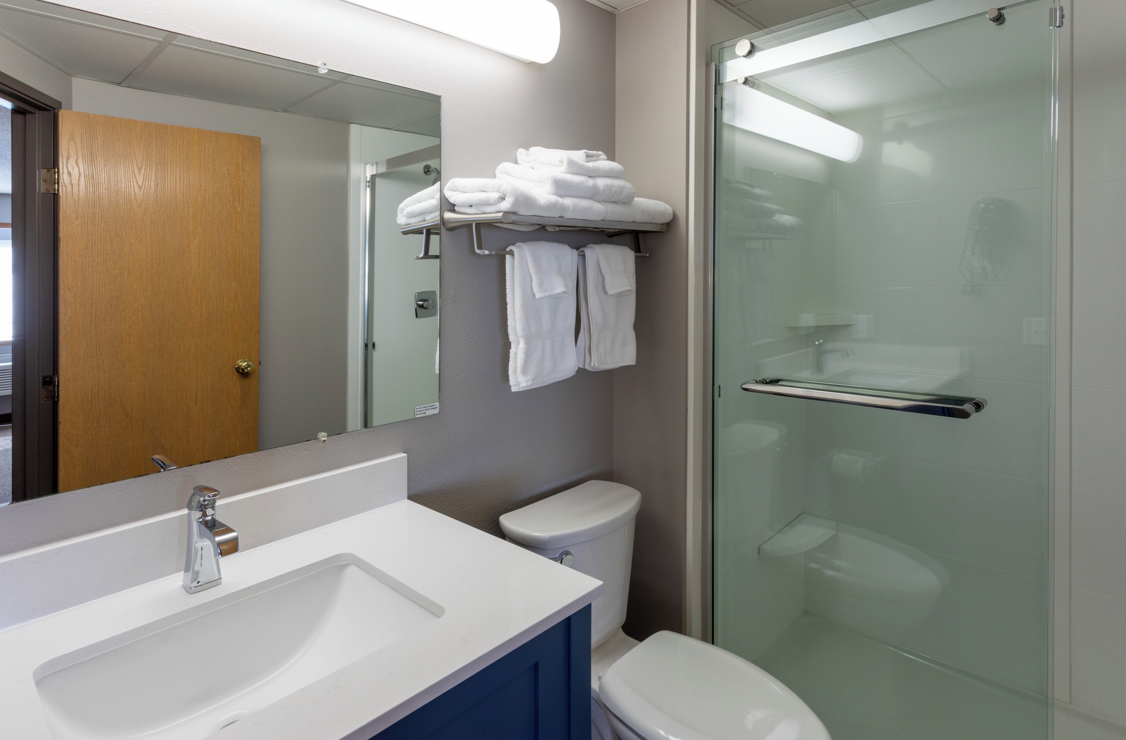 A modern bathroom with a white sink, a glass shower enclosure, and a mirror above the sink.