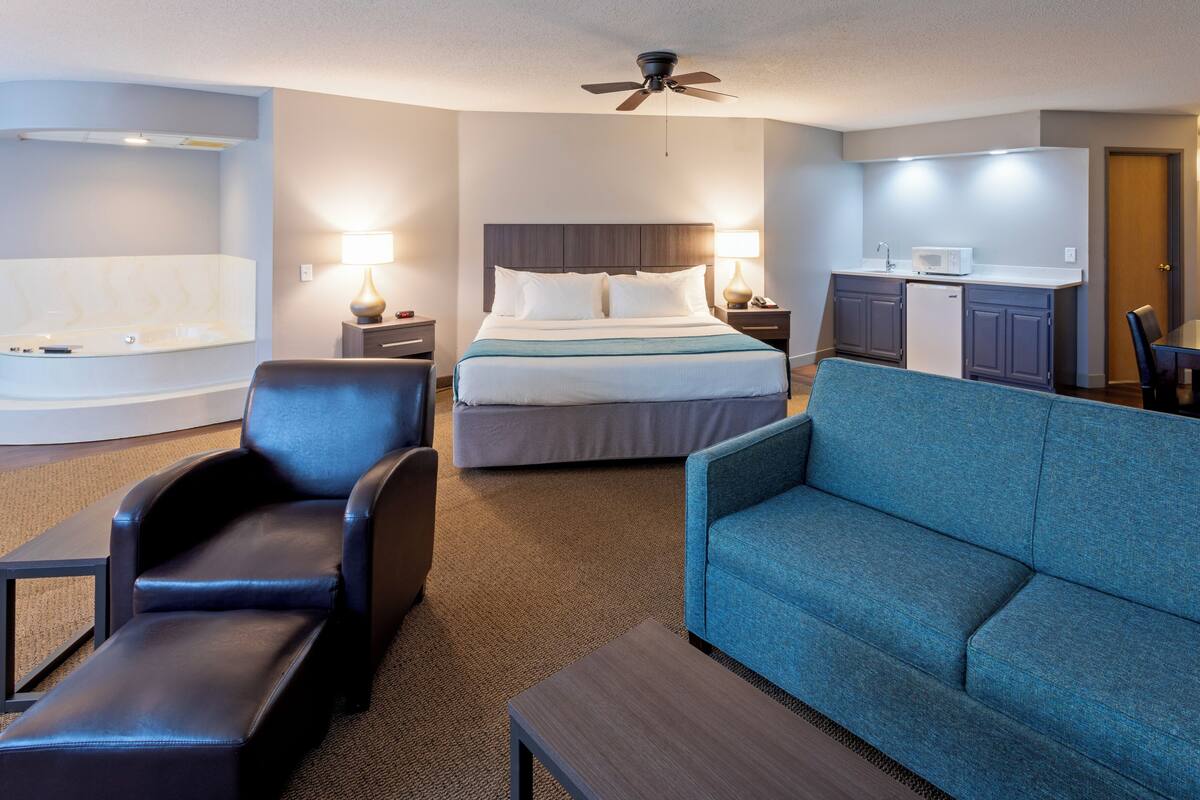 Una habitación de hotel con cama, escritorio, silla, sofá y ventilador de techo.