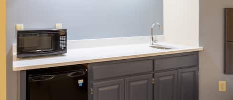 A compact kitchen with a built-in microwave, a sink, and a dishwasher.