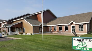 Un edificio de dos pisos con un patio cubierto y un letrero que indica que es Paynesville Inn & Suites.