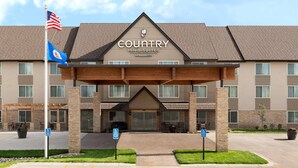 A Country Inn & Suites by Radisson building with a covered entrance, handicap parking, and a flagpole with the American flag.