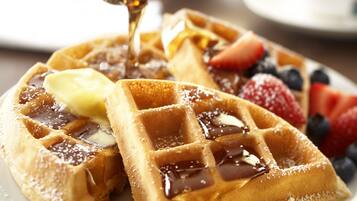 A plate of waffles with syrup and fruit toppings.
