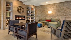 A living room with a fireplace, a clock, and a stone wall. - Country Inn & Suites by Radisson, St. Cloud West, MN (St Cloud)