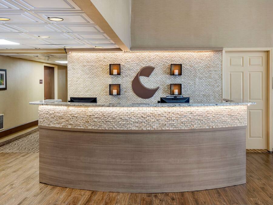 Una recepción con diseño de piedra y madera, una gran decoración en forma de luna creciente y cuatro lámparas fijadas a la pared.