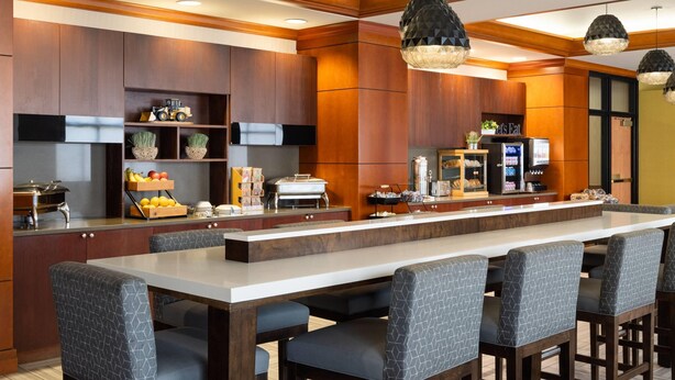 A modern kitchen with a long island, bar stools, and pendant lighting.