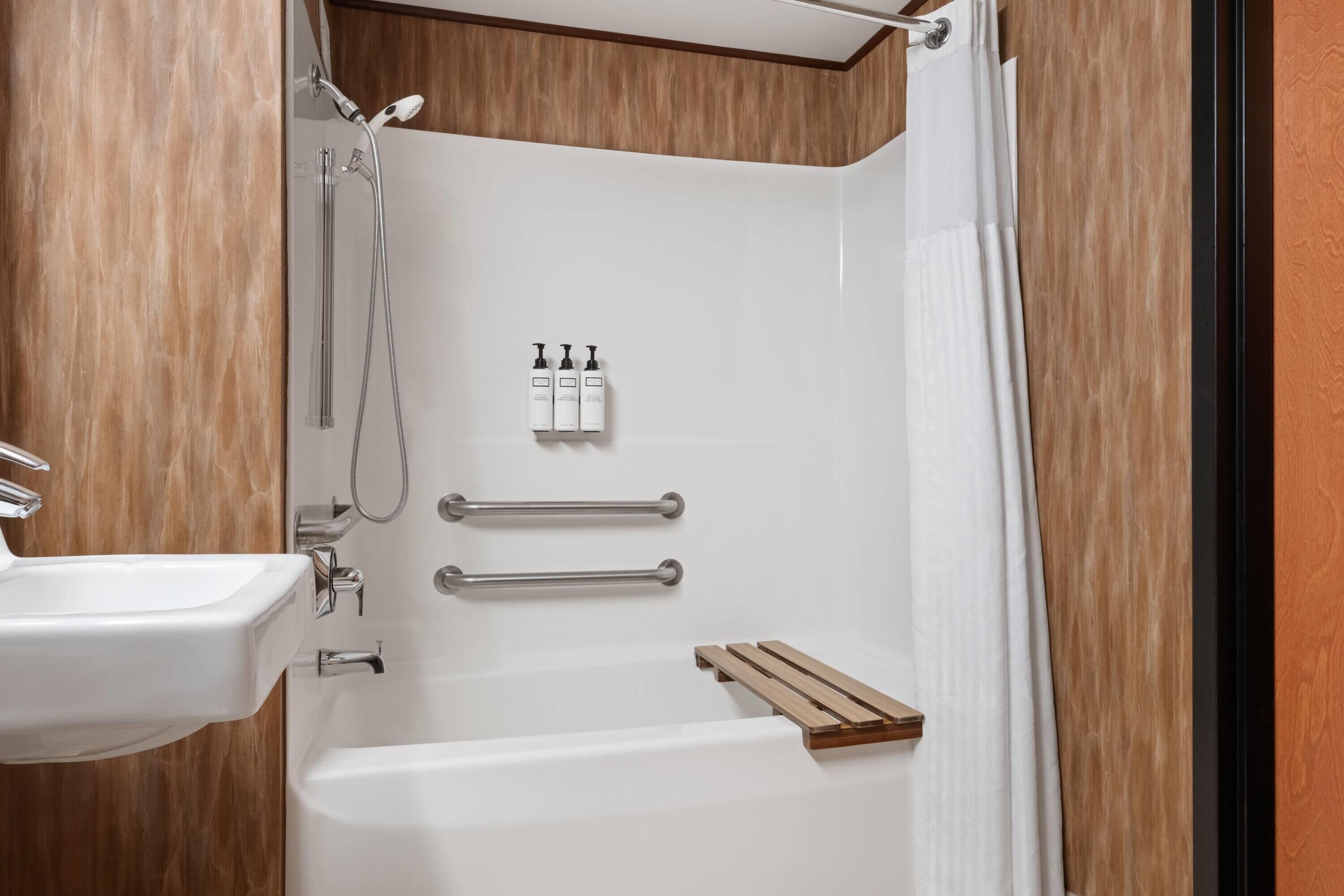 Un bagno moderno con una vasca da bagno bianca, un mobile bagno in legno e uno spazio doccia.