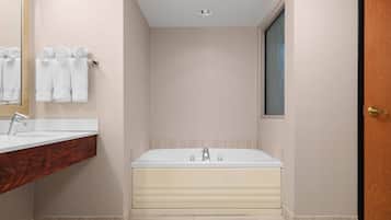 Un baño moderno con una bañera grande, un tocador de madera y un espejo.
