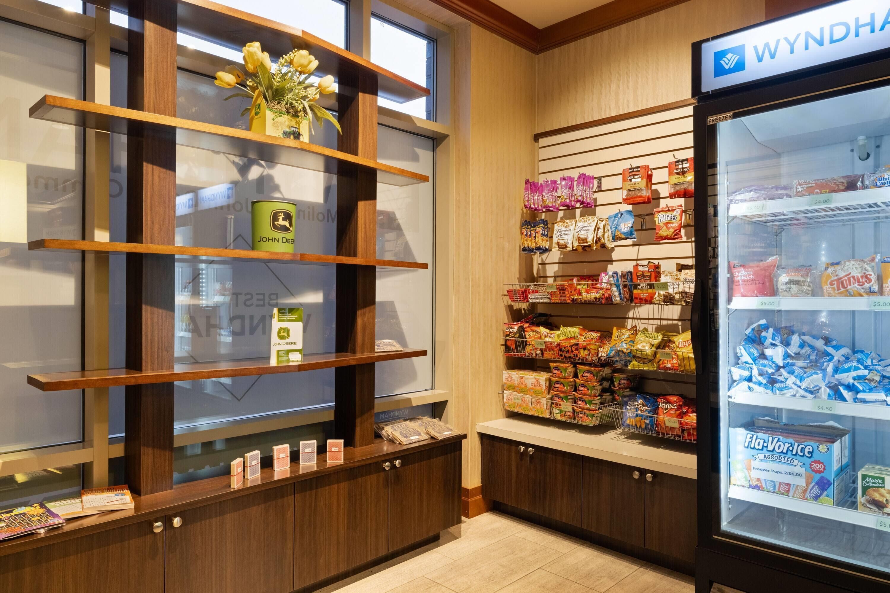 Un hall de hotel con estanterías de madera, una vitrina refrigerada y una variedad de aperitivos y bebidas.