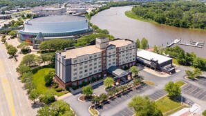 A large hotel with a central courtyard, a parking lot, and a river in the background.
