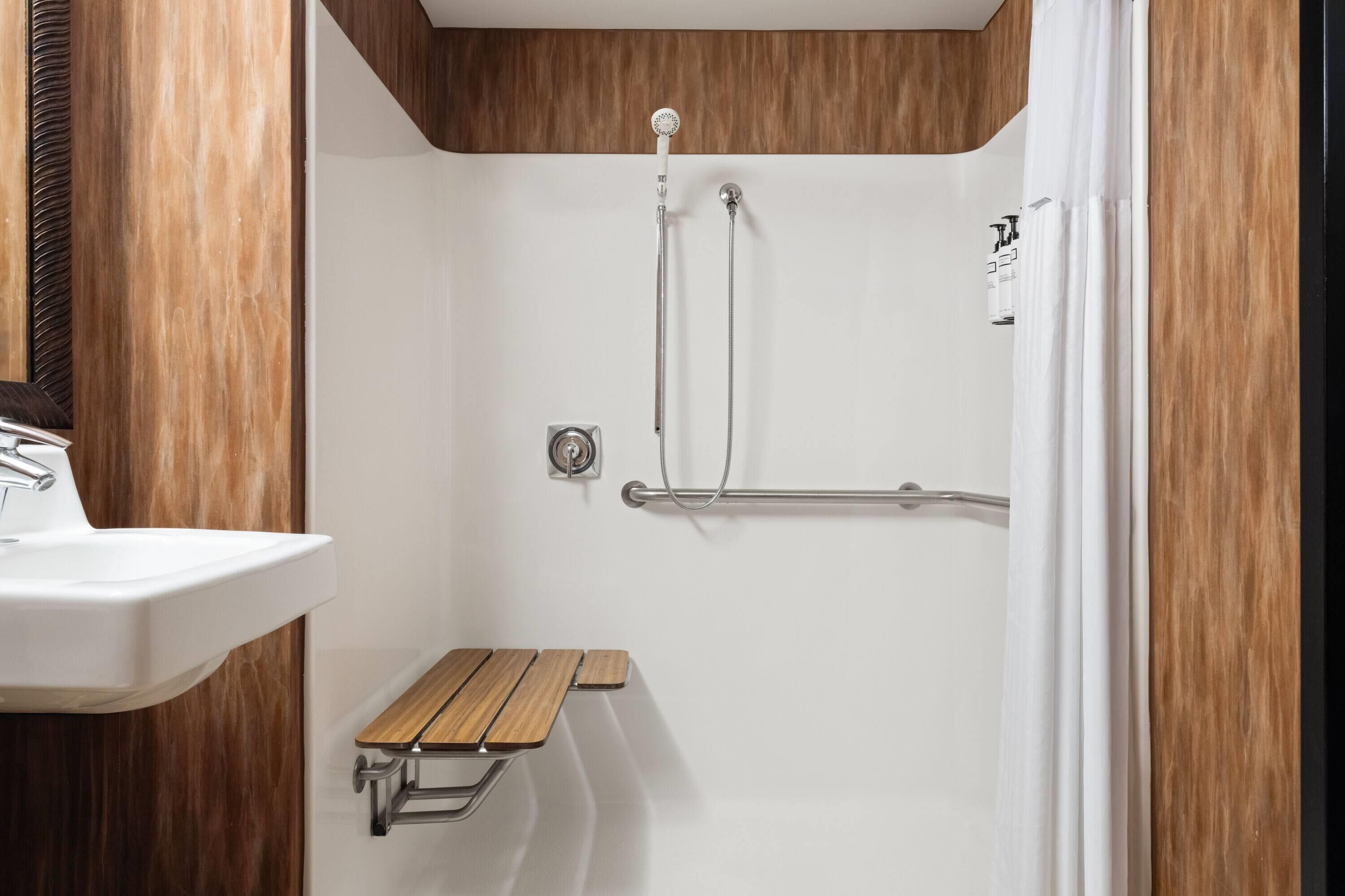 Un bagno moderno con doccia, lavandino e una panca in legno.