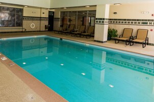 Una piscina interior con agua cristalina, rodeada de tumbonas y una pared de azulejos con un borde decorativo.
