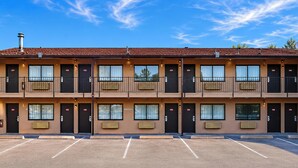 A multi-story motel with a parking lot in front. - Travel Inn By OYO Omaha (Omaha)