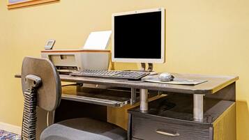 A computer desk with a monitor, keyboard, mouse, and a chair with a headrest.