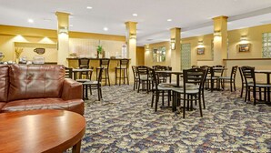 Un hall d’hôtel doté d’un canapé en cuir, de plusieurs tables et chaises, d’un comptoir de réception et d’un tapis à motifs.