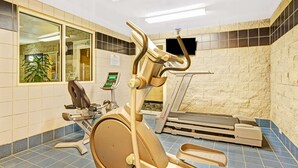 Une salle de remise en forme équipée d’appareils d’exercice, notamment un vélo d’appartement et un tapis de course, et dotée d’une grande fenêtre offrant une vue sur l’extérieur.