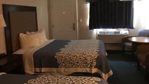 Een hotelkamer met een bed, een bureau, een stoel en een raam met gordijnen.