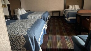 Een hotelkamer met twee bedden, een tafeltje, een stoel en een vloerkleed.