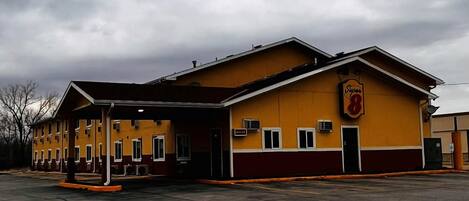 Un edificio amarillo con un letrero Super 8, un acceso cubierto y un estacionamiento.