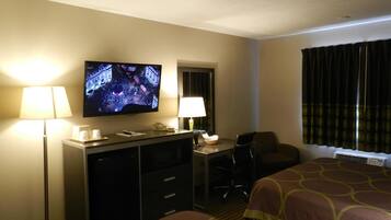 Habitación de hotel con televisor, escritorio, dos camas y ventana con cortinas.