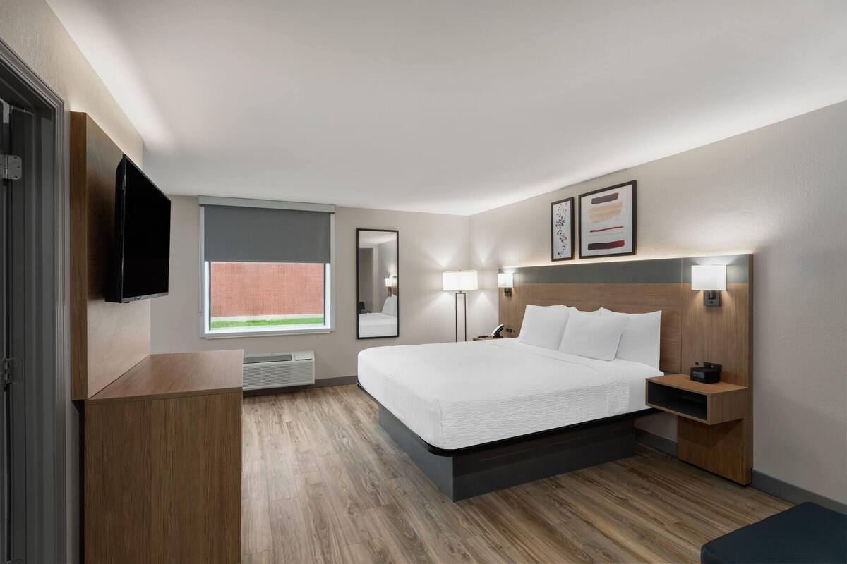 Ein modernes Hotelzimmer mit einem großen Bett, Nachttischlampen, einem Flachbildfernseher und einem Fenster mit Blick.