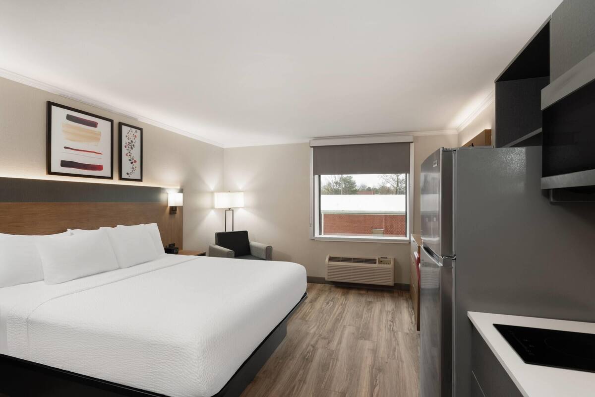 Ein Hotelzimmer mit Bett, Schreibtisch, Kühlschrank und einem Fenster mit Aussicht.