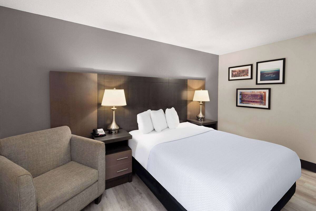 Ein Hotelzimmer mit einem großen Bett, einer Couch, zwei Nachttischen mit Lampen und drei gerahmten Bildern an der Wand.