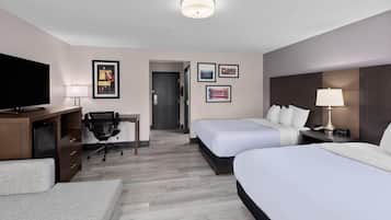 Una habitación de hotel con dos camas, un escritorio, un televisor y una silla.