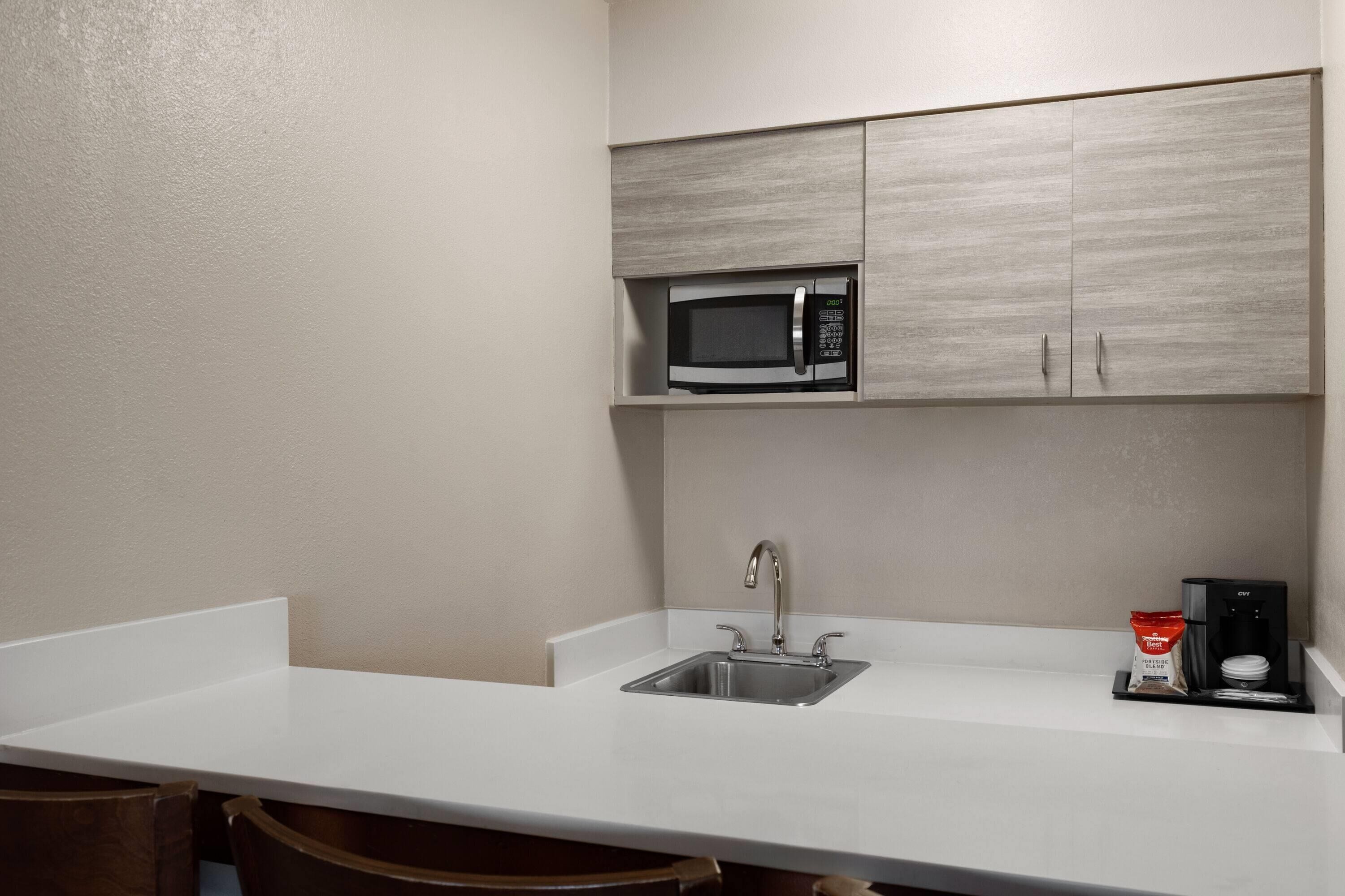 Una kitchenette equipada con microondas, un lavamanos y una cafetera.