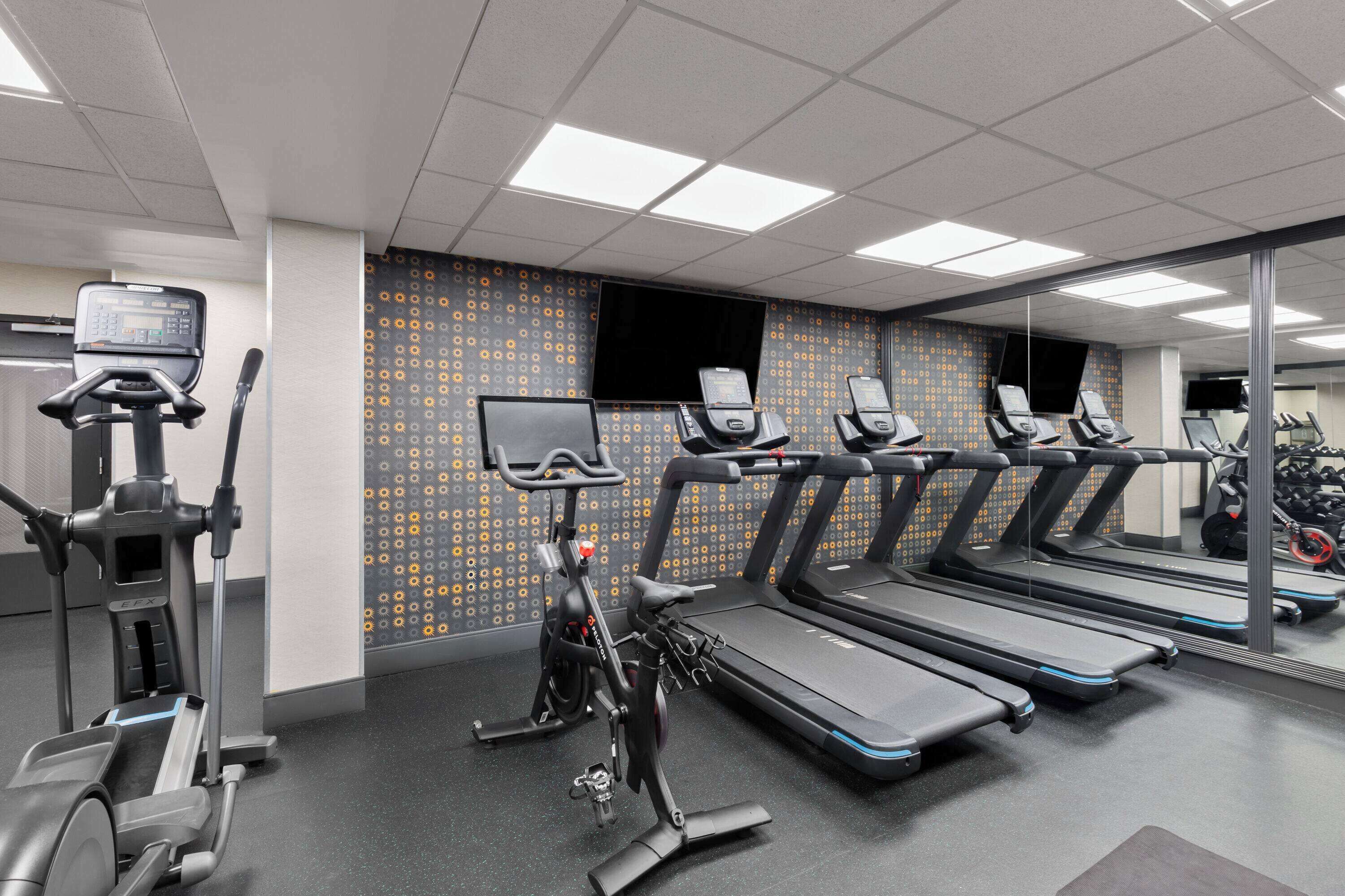 Un gimnasio con cintas de correr, bicicletas estáticas y elípticas.
