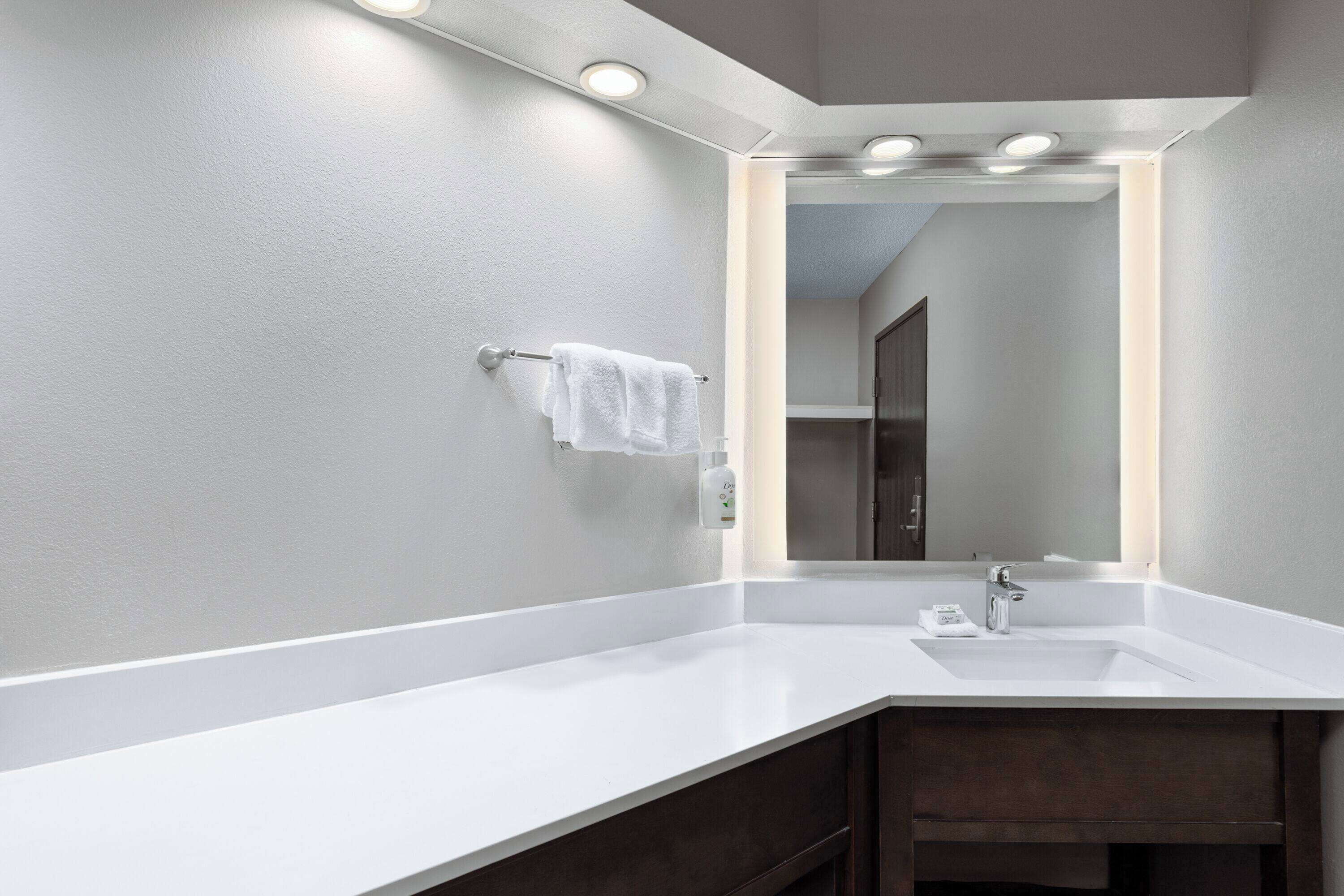 A modern bathroom with a white sink, a towel rack, and a mirror.