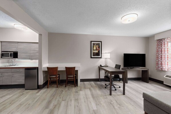 Una habitación de hotel moderna con kitchenette, comedor, televisor y zona de estar.