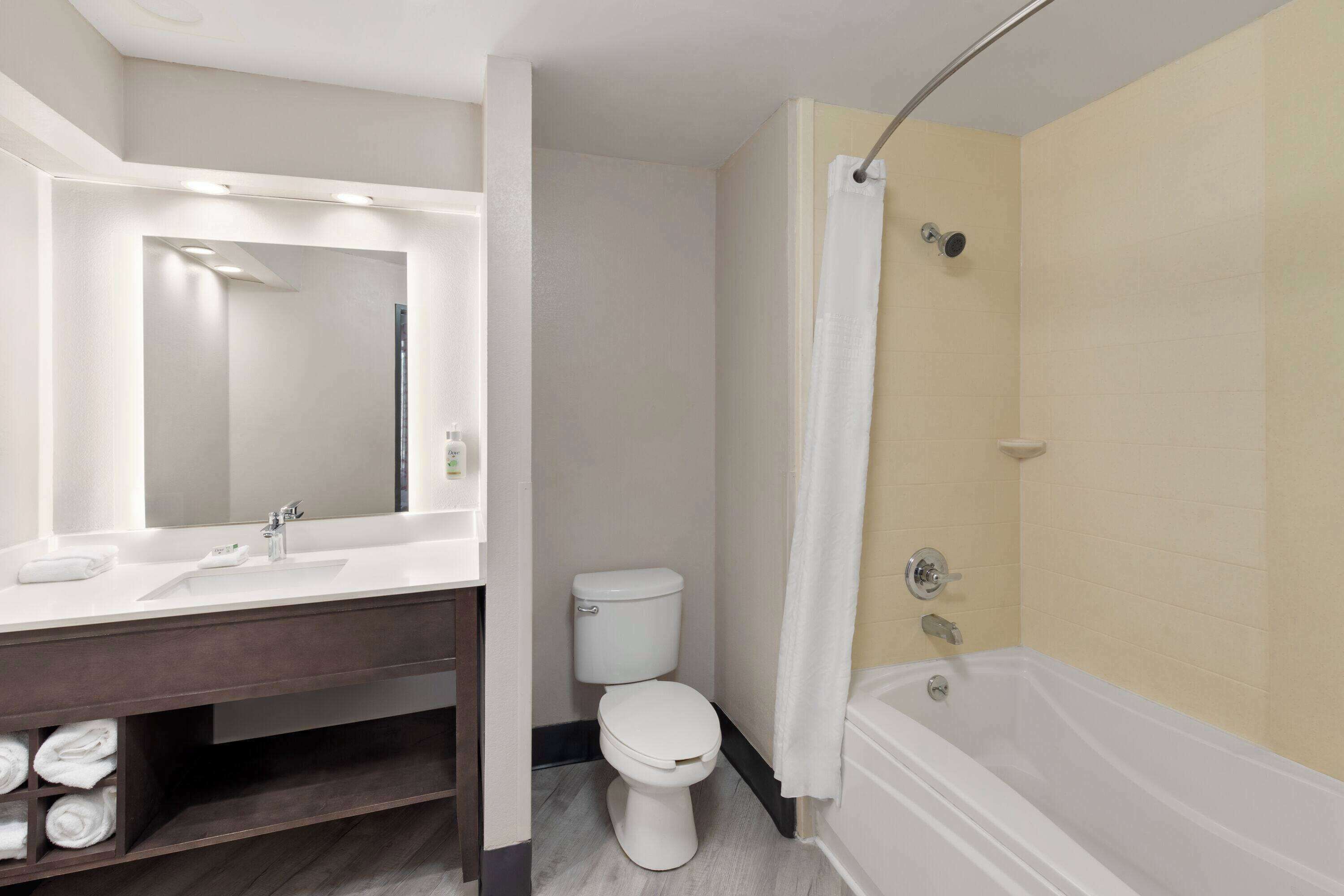 Ein Badezimmer mit weißem Waschbecken, Spiegel, Toilette und Badewanne.