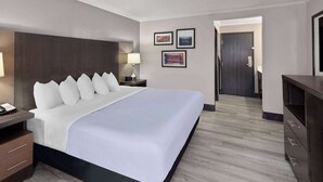 A hotel room with a large bed, bedside tables, a desk, and a wardrobe. There are framed pictures on the wall. - La Quinta Inn & Suites by Wyndham Goodlettsville - Nashville (Goodlettsville)