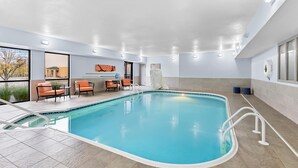 An indoor swimming pool with a tiled floor, a pool ladder, and a seating area with chairs and a table. - Hampton Inn Akron-Fairlawn (Akron)