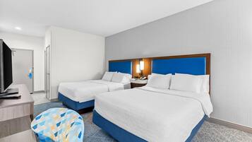 Une chambre d’hôtel avec deux lits, un bureau, une télévision et une chaise à motifs.