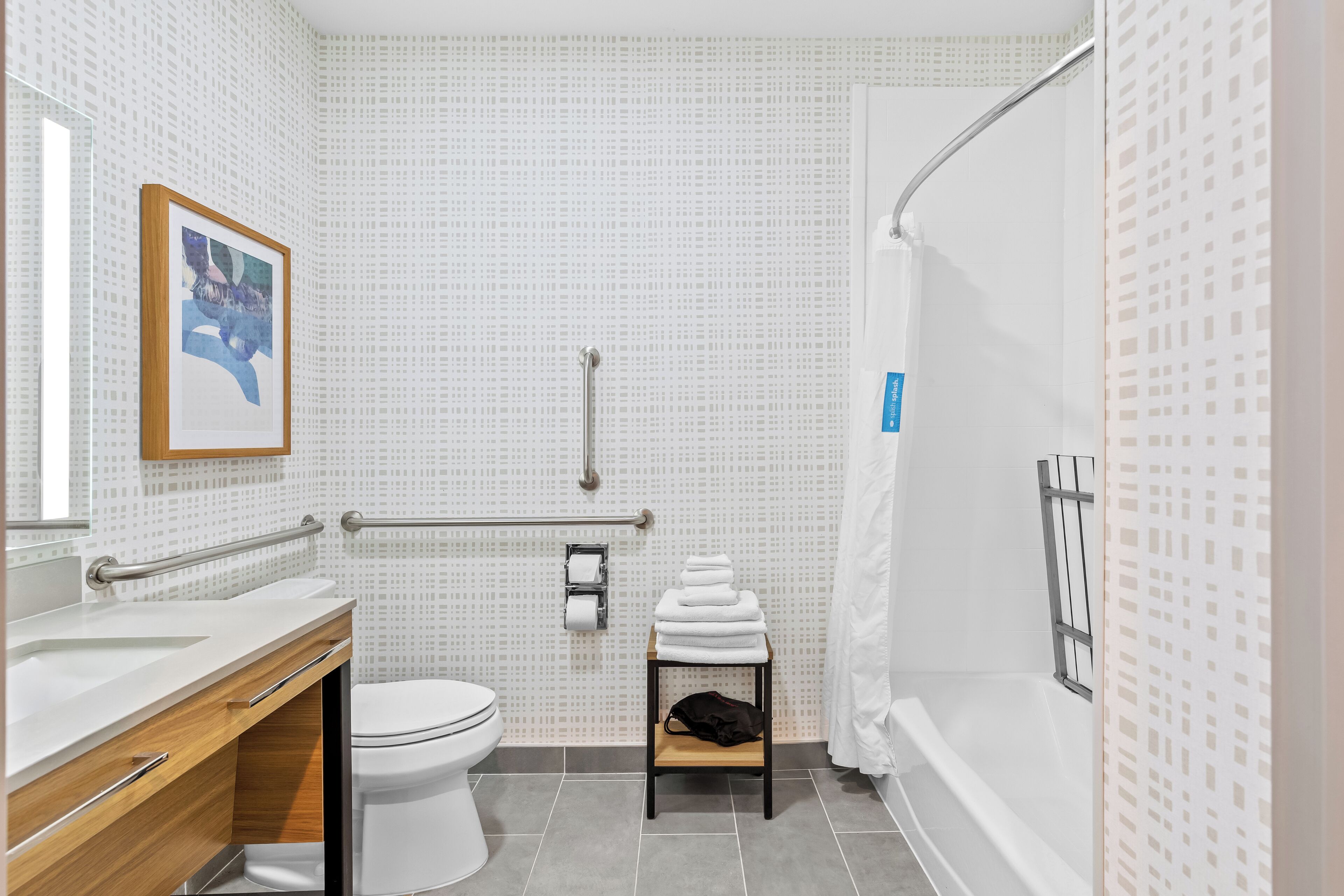 A modern bathroom with a white sink, toilet, and shower area.