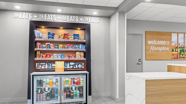 A snack display with various packaged foods and a refrigerated drink cooler. - Hampton Inn Akron-Fairlawn (Akron)