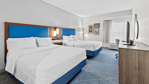 A hotel room with two beds, a desk, a chair, a large window with curtains, and a wall-mounted TV. - Hampton Inn Akron-Fairlawn (Akron)