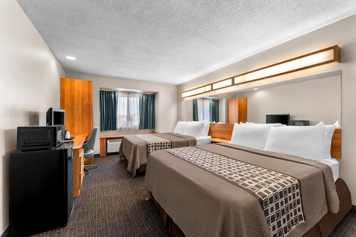 A hotel room with two beds, a desk, a TV, and a minibar.