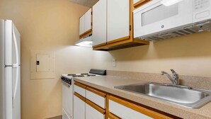 Una cocina compacta con electrodomésticos blancos, encimera de granito y armarios de madera.