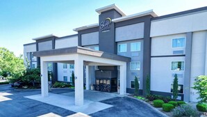 Een Sleep Inn & Suites hotel met een modern ontwerp, met een overdekte ingang en een aangelegde voortuin.