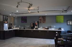 Una cocina moderna con una isla central, equipada con cafetera, estación de té y cristalería.